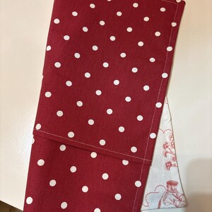 K&ouml;nnte beinhalten: Eine gefaltete Stoffserviette mit roten und wei&szlig;en Punkten auf wei&szlig;em Hintergrund. Die Serviette besteht aus einem weichen Stoff und hat einen gen&auml;hten Saum. Die wei&szlig;en Punkte sind gleichm&auml;&szlig;ig &uuml;ber die rote Oberfl&auml;che verteilt. Eine zweite Serviette mit rot-wei&szlig;em Blumenmuster ist teilweise sichtbar.