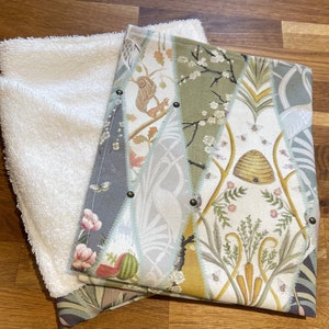 Peut inclure: Un gant de toilette blanc et moelleux &agrave; c&ocirc;t&eacute; d'un tissu d&eacute;coratif &agrave; motifs. Le tissu &agrave; motifs pr&eacute;sente divers motifs, dont un &eacute;cureuil, des abeilles et une ruche, dans des tons de vert, de gris et de cr&egrave;me. Les deux tissus sont sur une surface en bois.