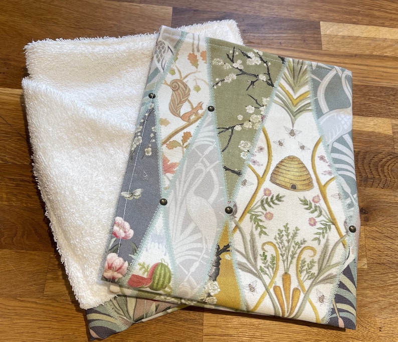 Peut inclure: Un gant de toilette blanc et moelleux &agrave; c&ocirc;t&eacute; d'un tissu d&eacute;coratif &agrave; motifs. Le tissu &agrave; motifs pr&eacute;sente divers motifs, dont un &eacute;cureuil, des abeilles et une ruche, dans des tons de vert, de gris et de cr&egrave;me. Les deux tissus sont sur une surface en bois.