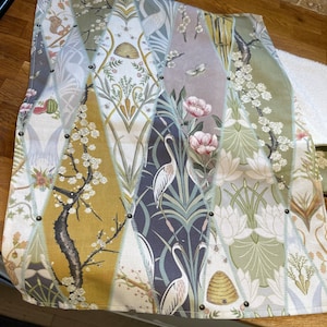 Peut inclure: Un textile d&eacute;coratif avec un motif patchwork pr&eacute;sentant divers motifs inspir&eacute;s de la nature. Le design comprend des motifs floraux, d'oiseaux et d'insectes dans des tons de vert, de jaune et de gris. Les bords sont fix&eacute;s avec de petits clous sombres.