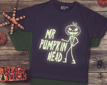 May include: A dark blue t-shirt with a glow-in-the-dark design featuring a pumpkin-headed stick figure with the text "Mr Pumpkin Head".