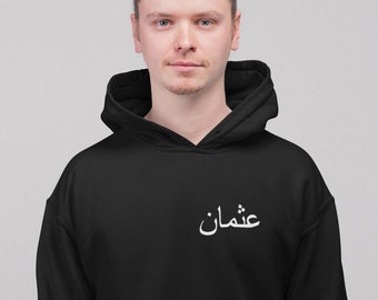 May include: Black hooded sweatshirt with the Arabic word "عمان" (Oman) printed in white on the front.