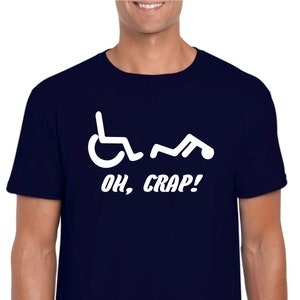 Puede incluir: Una camiseta azul marino con un gráfico blanco de una persona en silla de ruedas que se cae con el texto "OH, CRAP!"