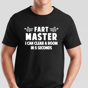 May include: Black t-shirt with the text "FART MASTER I CAN CLEAR A ROOM IN 5 SECONDS" in white. The shirt is a crew neck and is being worn by a person.