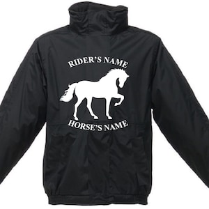 Op de afbeelding: Zwarte paardrijjas met een wit paard silhouet en de tekst "RIDER'S NAME" erboven en "HORSE'S NAME" eronder. De jas heeft een hoge kraag en twee voorzakken.