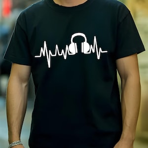 Könnte beinhalten: Ein schwarzes T-Shirt mit kurzen Ärmeln und einem weißen Grafikdruck auf der Brust. Das Design besteht aus einer durchgehenden horizontalen Herzschlaglinie, die in der Mitte des Pulswellenmusters ein Paar Kopfhörer integriert.