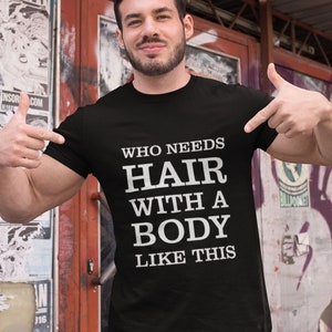 Op de afbeelding: Een zwart T-shirt met witte tekst die "Wie heeft haar nodig met een lichaam als dit" zegt.