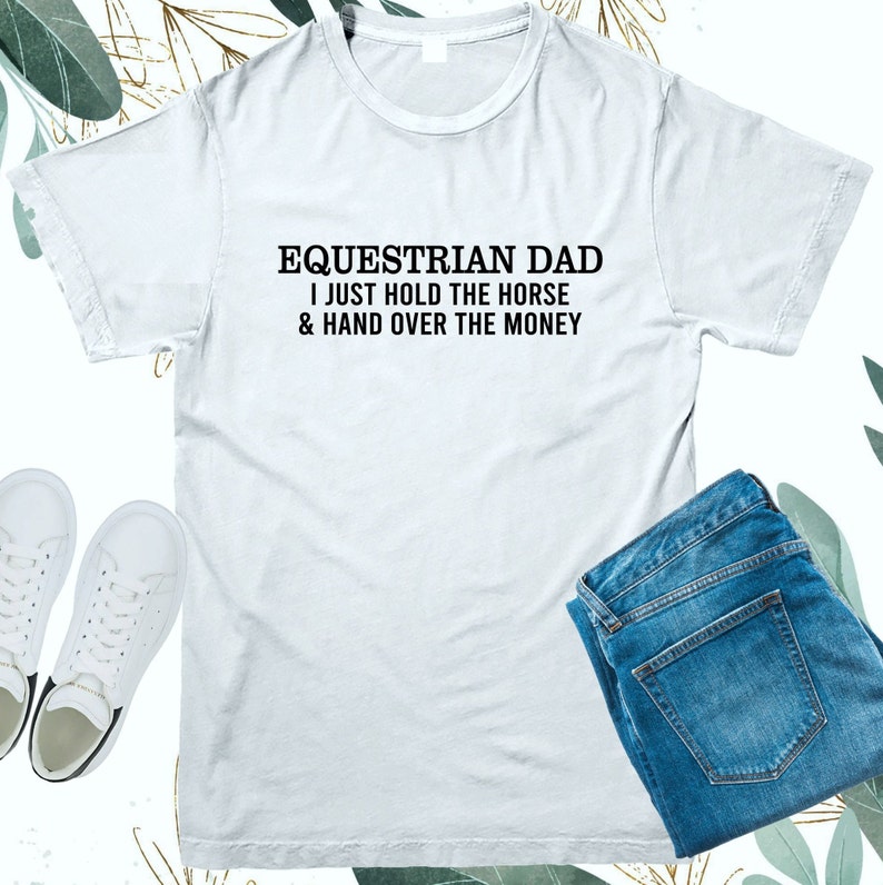 May include: White t-shirt with black text that reads "Equestrian Dad I just hold the horse & hand over the money"
