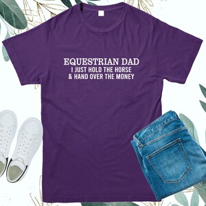 May include: Purple t-shirt with white text that reads "Equestrian Dad I just hold the horse & hand over the money".