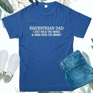 May include: A royal blue t-shirt with white text that reads "Equestrian Dad I just hold the horse & hand over the money".