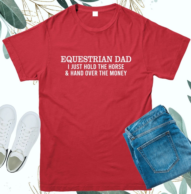 May include: Red t-shirt with white text that reads "Equestrian Dad I just hold the horse & hand over the money".