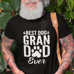 May include: Black t-shirt with the text "BEST DOG GRANDAD EVER" in white, featuring paw prints. The shirt is worn by a person with a white beard and tattoos.