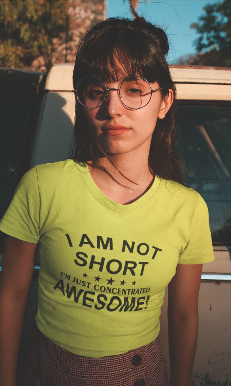 Puede incluir: Una persona con una camiseta verde lima con el texto "I AM NOT SHORT I'M JUST CONCENTRATED AWESOME!" en negro. La persona lleva gafas redondas y tiene el pelo oscuro.