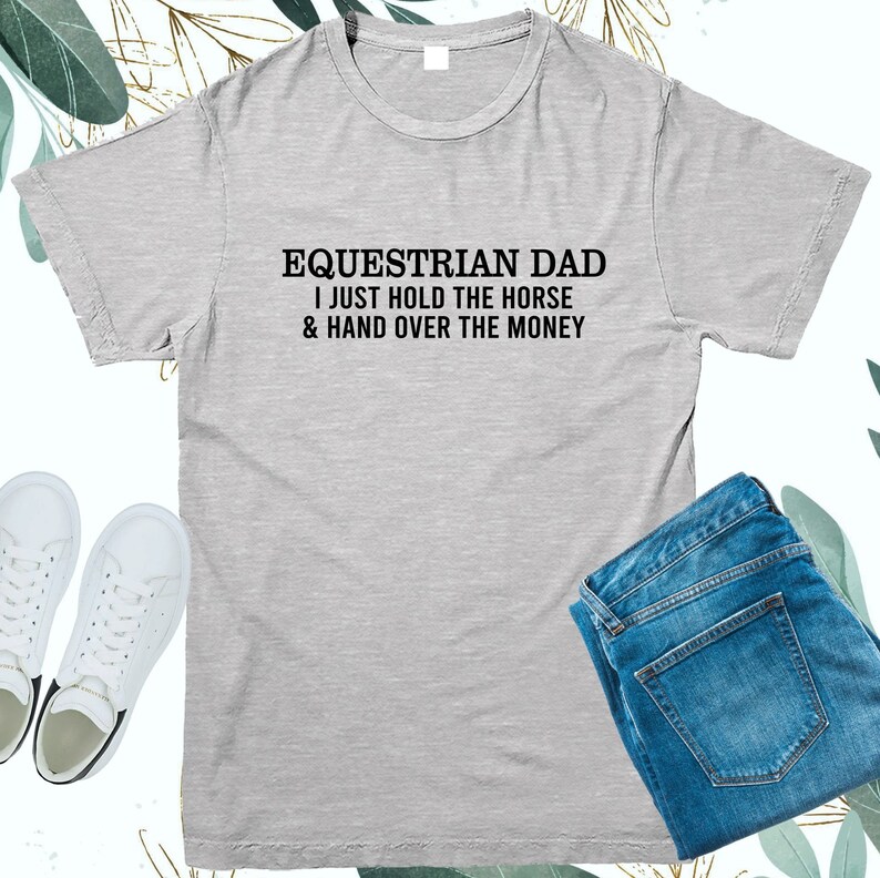 May include: Gray t-shirt with the text "Equestrian Dad I just hold the horse & hand over the money" printed in black.