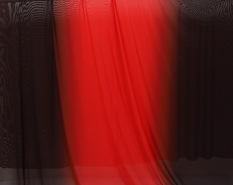 Puede incluir: Una tela transparente con un diseño degradado, que transiciona de negro en la parte superior e inferior a un rojo vibrante en el centro. La tela está drapeada sobre un marco de madera, mostrando su color y textura.