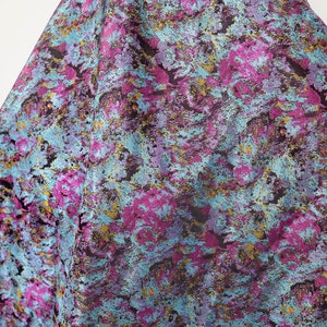 May include: A fabric with a blue, pink, and gold abstract pattern. The fabric has a textured, woven look.