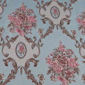 May include: A blue fabric with a repeating pattern of pink and brown flowers and ornate scrollwork.