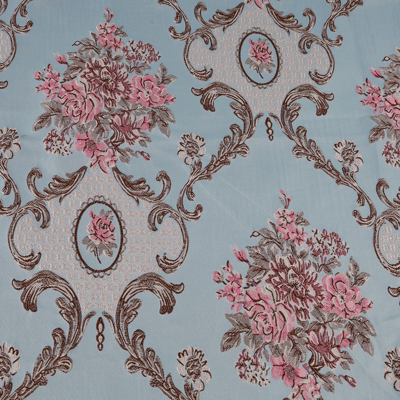 May include: A blue fabric with a repeating pattern of pink and brown flowers and ornate scrollwork.