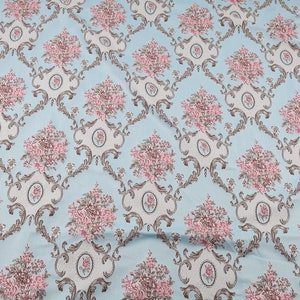 May include: A light blue fabric with a repeating pattern of pink and brown floral bouquets in ornate frames.