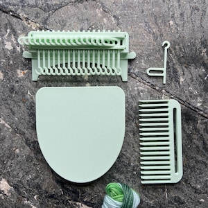 May include: A set of light green plastic knitting tools, including a loom, a comb, a hook, and a ball of green and white yarn.