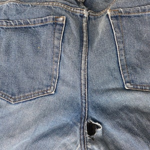 Pu&ograve; includere: Un paio di jeans blu denim con un piccolo buco nella zona del cavallo. I jeans hanno due tasche posteriori.