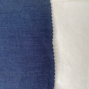Pu&ograve; includere: Primo piano di due campioni di tessuto. Il campione a sinistra &egrave; un tessuto denim blu scuro con un bordo a festoni. Il campione a destra &egrave; un tessuto bianco.