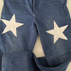 Könnte beinhalten: Eine blaue Jeans mit zwei weißen Sternen auf der Vorderseite.