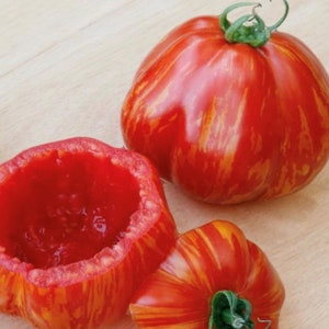 May include: Three striped red and yellow tomatoes. One tomato is whole, and two are cut open, revealing the red flesh inside.