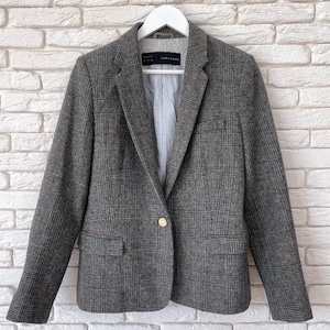 May include: A gray plaid blazer with a single gold button closure. The blazer has a notched lapel, two front pockets, and a striped lining. The label reads "ZARA BASIC".