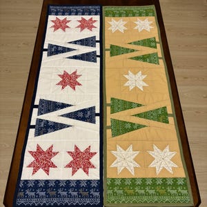 Peut inclure: Deux chemins de table matelassés. L'un est blanc avec des étoiles rouges et des accents bleus, l'autre est doré avec des étoiles blanches et des accents verts. Les deux ont un motif de rennes décoratif sur le bord inférieur.