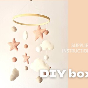Può includere: Un kit fai-da-te per un mobile per bambini con un cerchio di legno, nuvole di feltro, stelle e pon pon. Il kit include materiali e istruzioni. Scatola fai-da-te.
