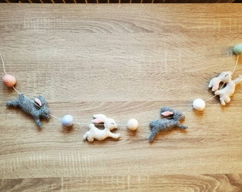 Puede incluir: Una guirnalda de conejitos de fieltro grises y blancos, con bolas de fieltro de colores pastel. Los conejitos tienen orejas rosas y están ensartados en una cuerda blanca. Un artículo decorativo para Pascua o primavera.