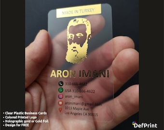 Può includere: Un biglietto da visita in plastica trasparente con lettere dorate e un ritratto dorato di un uomo con la barba. Il testo sulla carta recita "ARON IMANI", "310-666-4622", "USA 310-666-4622", "aron_imani", "aronimani@gmail.com", "1013 Maple Ave", "Los Angeles CA 90015" e "MADE IN TURKEY".