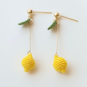 Puede incluir: Un par de pendientes de aro dorados con abalorios de lim&oacute;n tejidos a crochet y hojas verdes. Los pendientes est&aacute;n sobre un fondo blanco.  Little Crochet Flower by Layla.