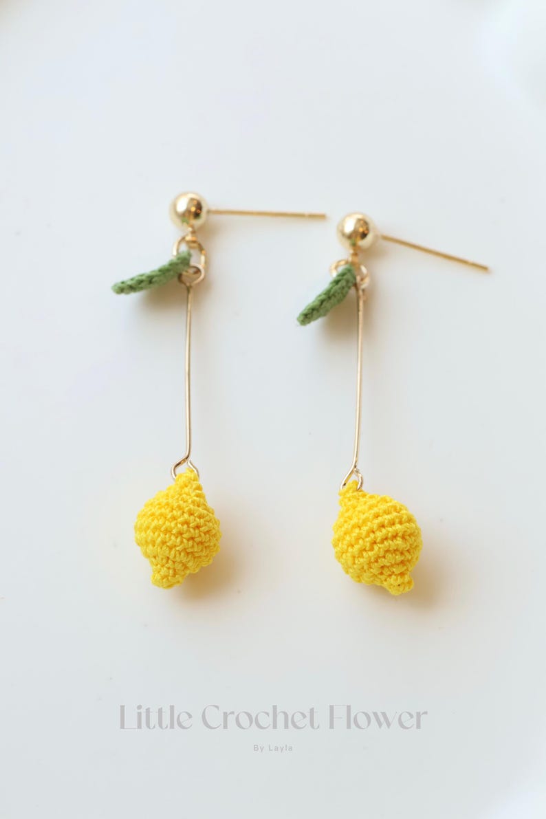 Puede incluir: Un par de pendientes de aro dorados con abalorios de lim&oacute;n tejidos a crochet y hojas verdes. Los pendientes est&aacute;n sobre un fondo blanco.  Little Crochet Flower by Layla.