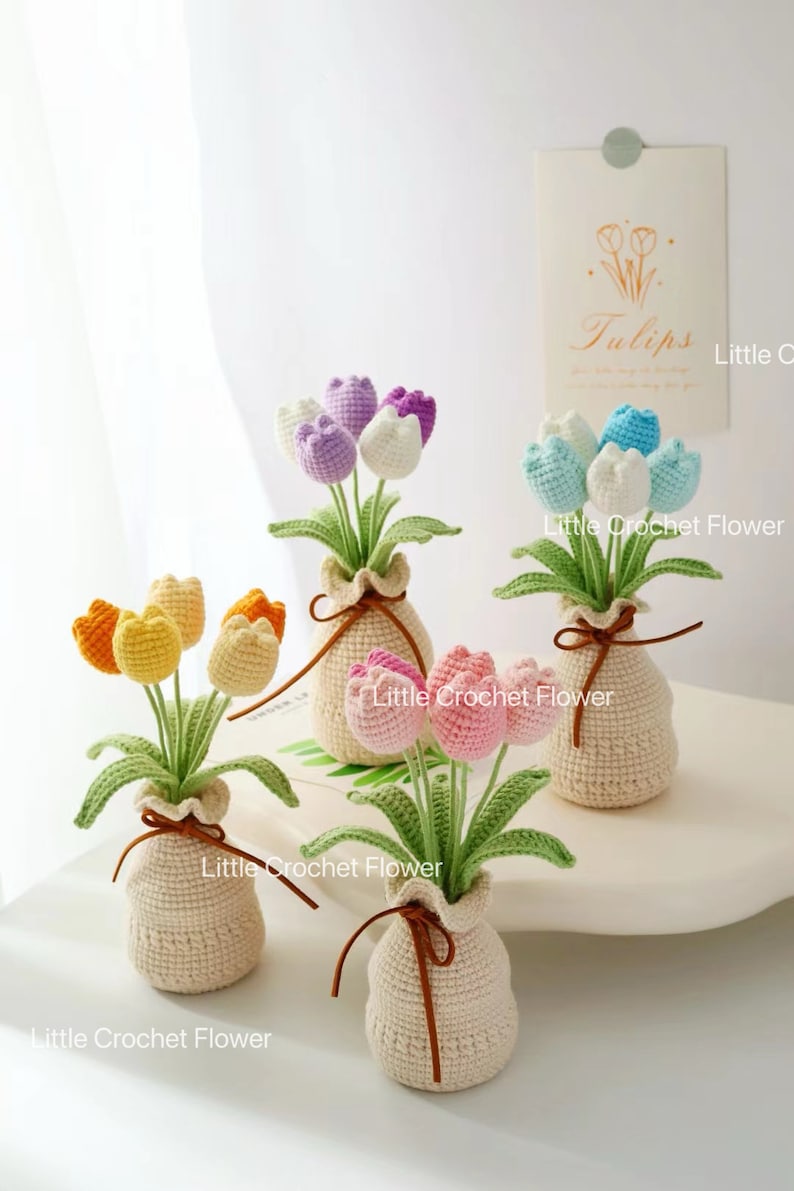 May include: Handmade crochet tulip flowers in small beige vases, tied with brown string. The tulips are in shades of yellow, orange, pink, purple, and blue. The text "Little Crochet Flower" is visible.