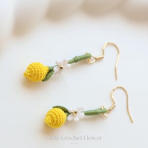 Puede incluir: Un par de pendientes de lim&oacute;n hechos a crochet con detalles de flores blancas y ganchos dorados. Los pendientes son hechos a mano y tienen un dise&ntilde;o delicado.
