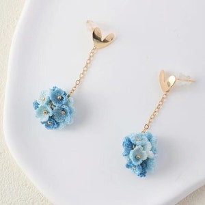 Könnte beinhalten: Ein Paar blaue und hellblaue blütenförmige Ohrringe mit goldenen herzförmigen Oberteilen und goldenen Ketten.