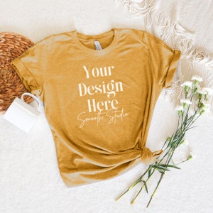 May include: A mustard yellow t-shirt with rolled up sleeves, laying flat on a white surface. The shirt has the text "Your Design Here Smooth Studio" printed on the front.