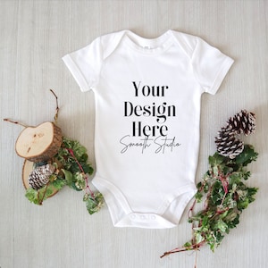 May include: White baby onesie with short sleeves and snaps at the bottom. The onesie has the text "Your Design Here" and "Smooth Studio" printed on the front.