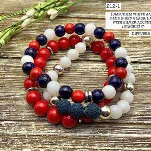 Op de afbeelding: Drie gestapelde armbanden met witte jade, blauwe en rode glazen kralen en lavakralen met zilveren accenten. De armbanden zijn gelabeld "212-1 DIFFUSER SET".