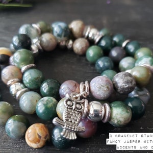 May include: Three-strand bracelet stack made with 10mm green, brown, and gray jasper beads. The bracelet has silver accents and a silver owl charm.  3 Bracelet Stack. 10mm Fancy Jasper with Silver Accents and Charm.