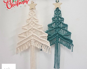 Könnte beinhalten: Zwei Makramee-Weihnachtsbaumschmuckstücke, die an Haken an einem Holzregal hängen. Der Baum links ist cremefarben und der Baum rechts ist blaugrün.