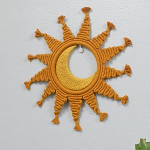Peut inclure: Une suspension murale en macramé en forme de soleil avec une lune croissante au centre. Le soleil est fait de cordon jaune moutarde et a 12 points. La lune est faite d'un cordon jaune plus clair.