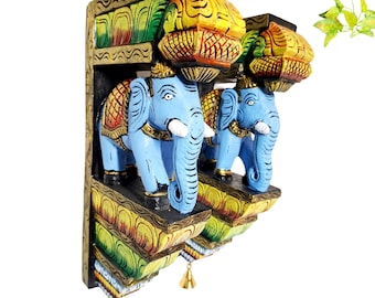 Peut inclure: Une paire de supports muraux en bois ornés d'éléphants bleu clair peints à la main avec des défenses blanches. Les supports présentent des motifs sculptés aux couleurs vives jaune, vert et rouge, avec une petite cloche en laiton à la base.
