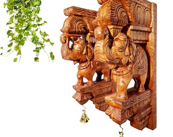 May include: Two hand-carved wooden wall brackets featuring elephant figures with trunks raised, intricate geometric patterns, and a polished finish. Each bracket includes a small, hanging brass-colored metal bell suspended from the base.