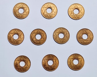 Könnte beinhalten: Zehn goldfarbene Münzen mit einem Davidstern-Design und dem Text "WEST AFRICA" und "1 SH 1952" am Rand.