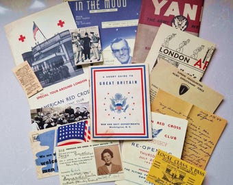 May include: A collection of vintage paper ephemera, including a guide to Great Britain, a pamphlet for the American Red Cross, and a program for a dance event. The papers are printed with red, white, and blue colors and feature images of the American flag and a building.