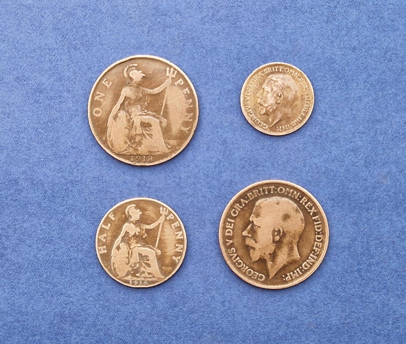 May include: Four antique British coins on a blue background. Two larger coins show a seated woman, with the text "ONE PENNY" and "HALF PENNY". The other two coins feature a profile of a man.