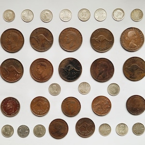 Peut inclure: Collection de pièces de monnaie australiennes anciennes, dont des pennies et des petites dénominations en argent, disposées sur une surface blanche. Les pennies en cuivre présentent des portraits et le kangourou emblématique.